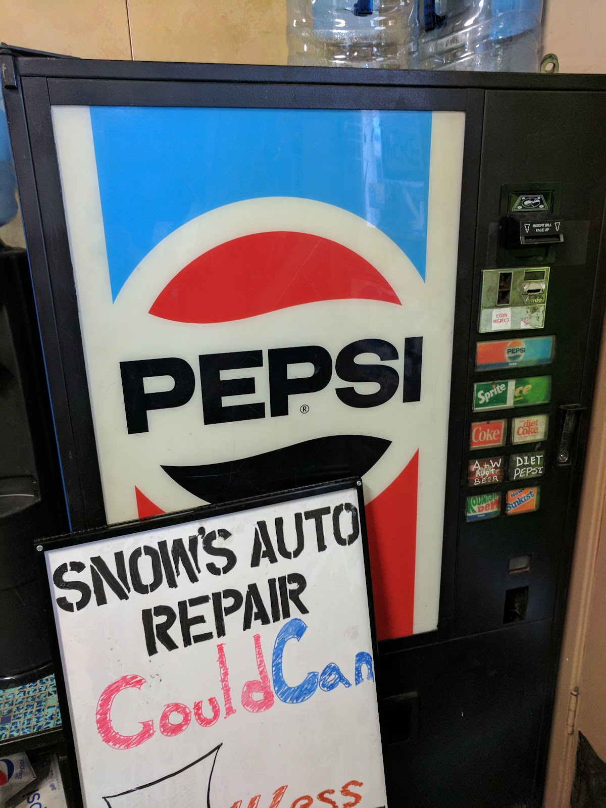 Inside the office at Snow's Auto Repair, a vintage Pepsi machine beside a hand lettered shop sign